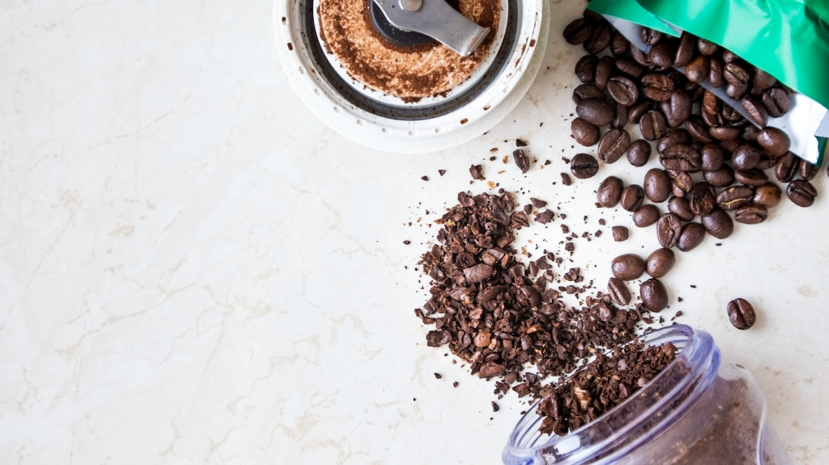 a blender filled with coffee beans next to a bag of coffee beans