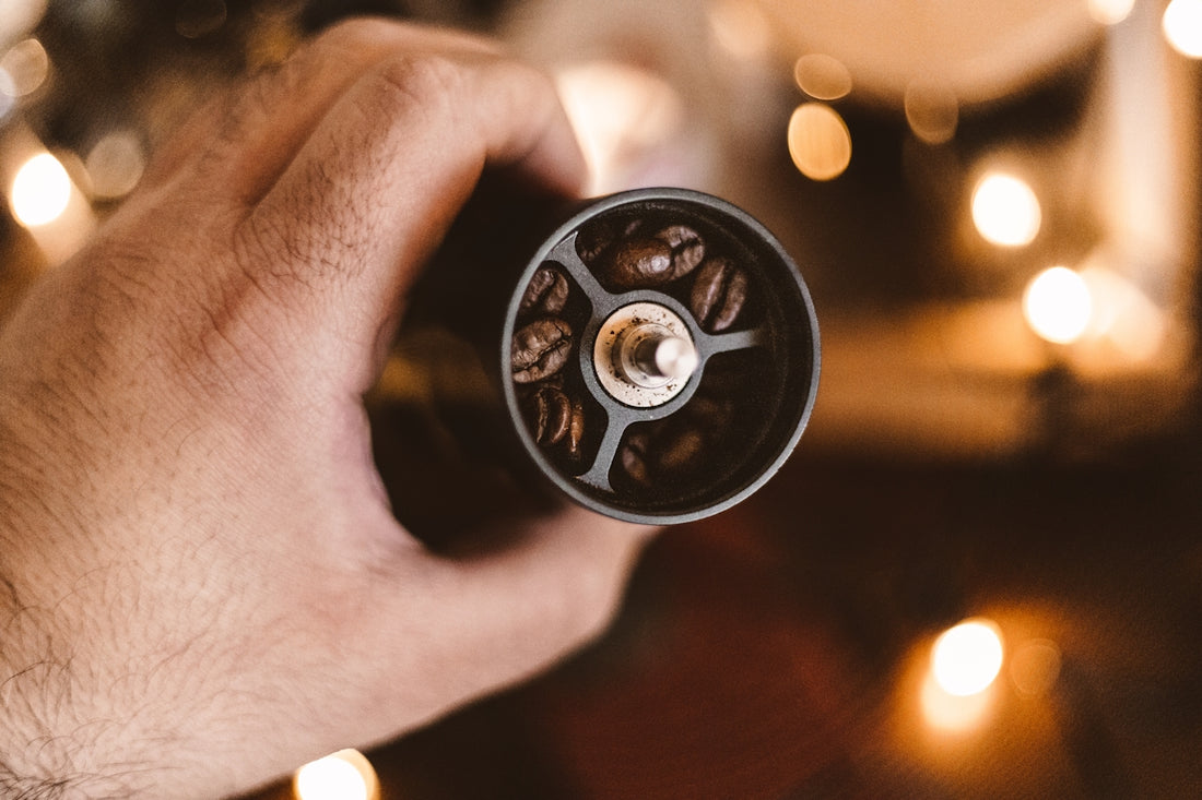 a hand holding a coffee grinder with coffee beans in it