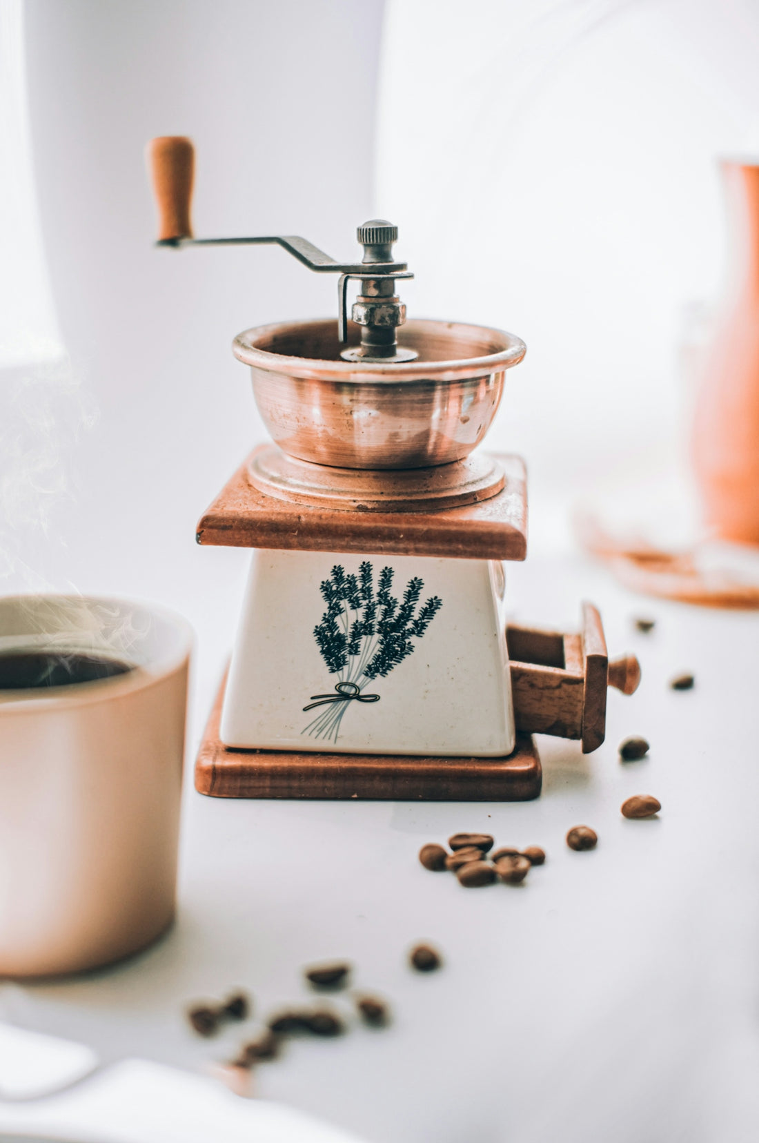 a coffee grinder sitting on top of a table next to a cup of coffee