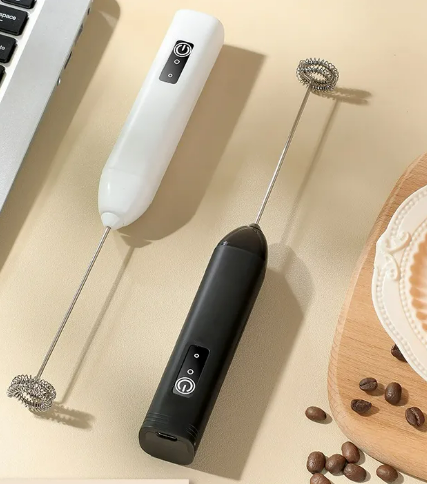 Pair of black and white electric milk frothers displayed together in a minimalist, aesthetic setting